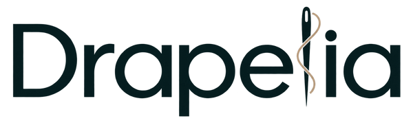 The logo for Drapealia, featuring the word 'Drapealia' in a dark teal serif font with a stylized vertical leaf-like 'i' in gold, set against a solid white background.